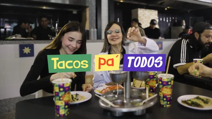 Comensales en Más Salsa con el letrero Tacos Pa' Todos de la campaña