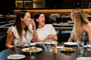 Tres amigas riendo en una mesa de Meza